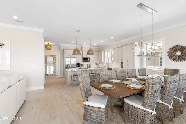 dining area with light hardwood / wood-style flooring, a notable chandelier, and crown molding