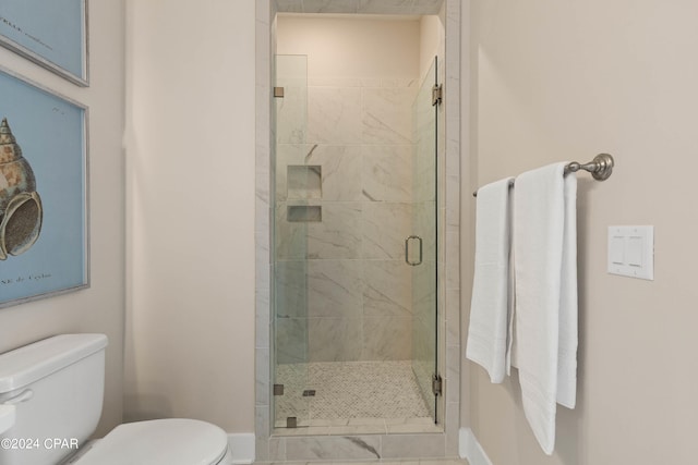 bathroom featuring a shower with shower door and toilet