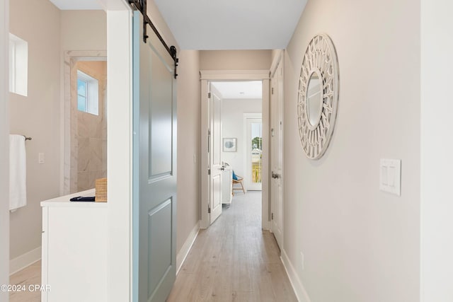 hallway featuring a barn door and light wood-type flooring