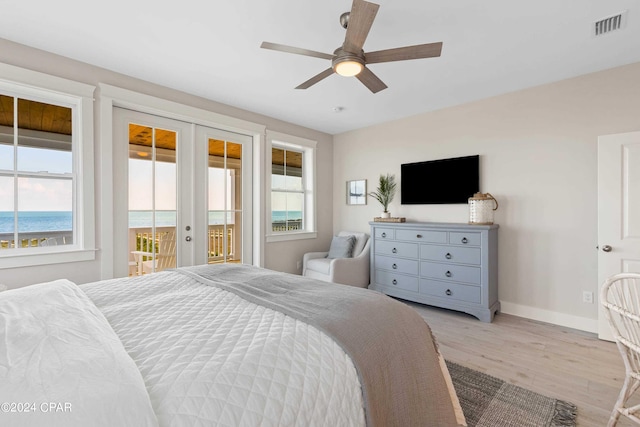 bedroom with french doors, access to outside, ceiling fan, a water view, and light hardwood / wood-style flooring