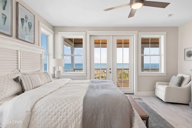 bedroom featuring access to outside, french doors, a water view, ceiling fan, and multiple windows