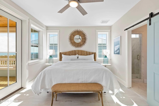 bedroom with ceiling fan, a barn door, ensuite bathroom, and multiple windows