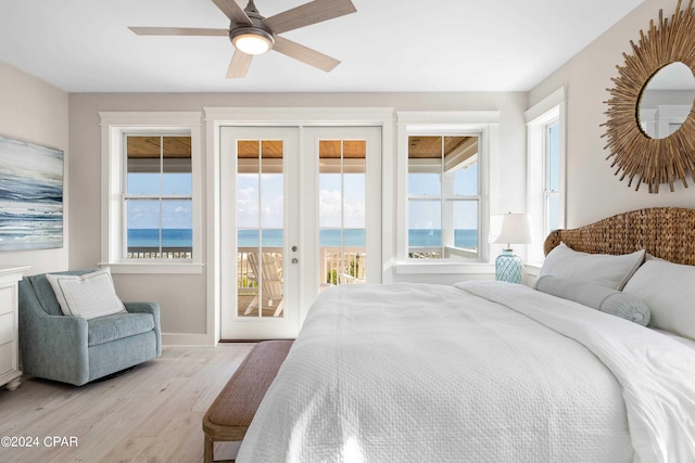 bedroom with access to exterior, french doors, ceiling fan, a water view, and light hardwood / wood-style floors