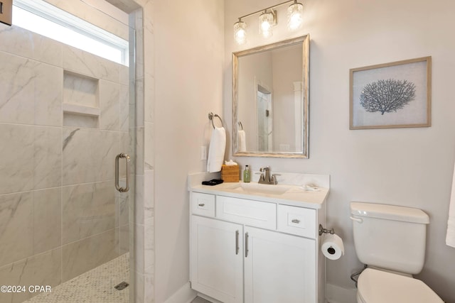 bathroom featuring a shower with door, vanity, and toilet