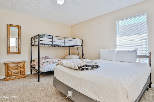 bedroom with ceiling fan, carpet, and a textured ceiling