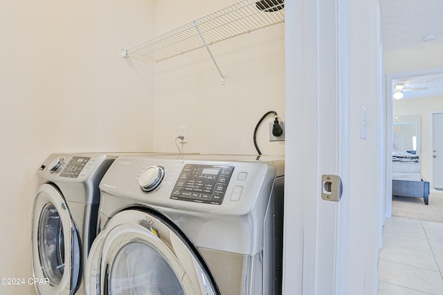 clothes washing area with light tile patterned floors, a textured ceiling, and washer and dryer