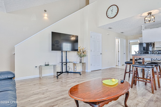 living room featuring a high ceiling, a textured ceiling, and light wood-type flooring