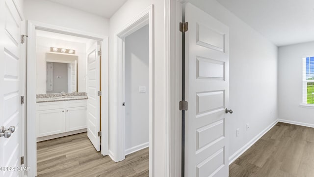 corridor featuring light wood-type flooring and sink