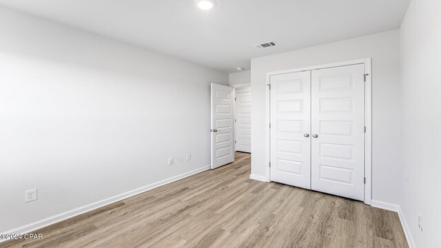 unfurnished bedroom with a closet and light wood-type flooring