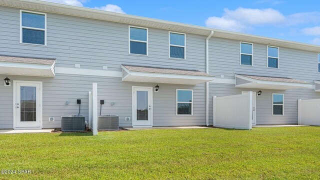 back of property with central AC and a lawn