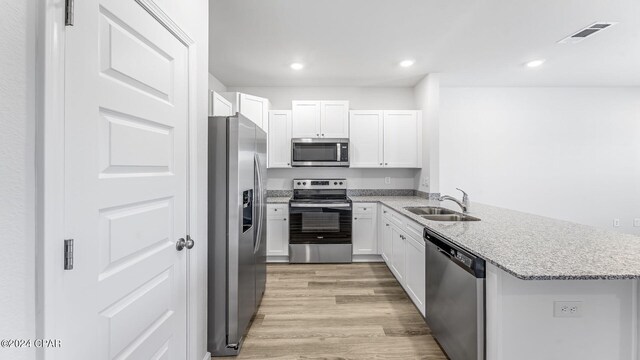 kitchen with white cabinets, light wood-type flooring, stainless steel appliances, and sink