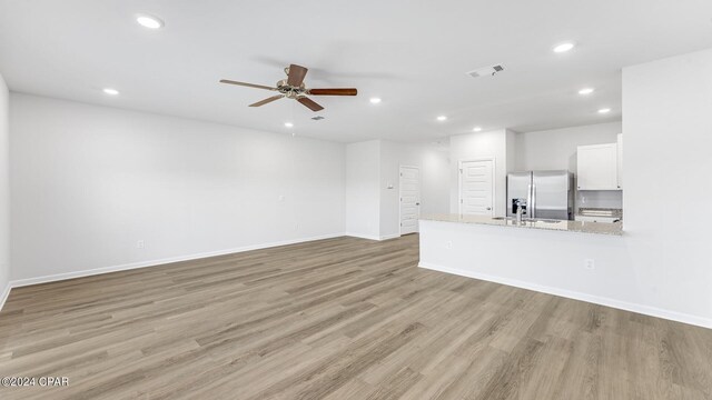 unfurnished living room featuring ceiling fan and light wood-type flooring