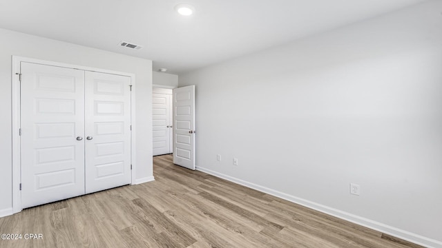 unfurnished bedroom with light hardwood / wood-style floors and a closet