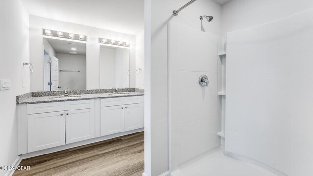 bathroom with hardwood / wood-style flooring, vanity, and walk in shower