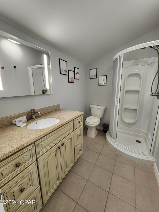 bathroom with toilet, tile patterned flooring, vanity, and walk in shower