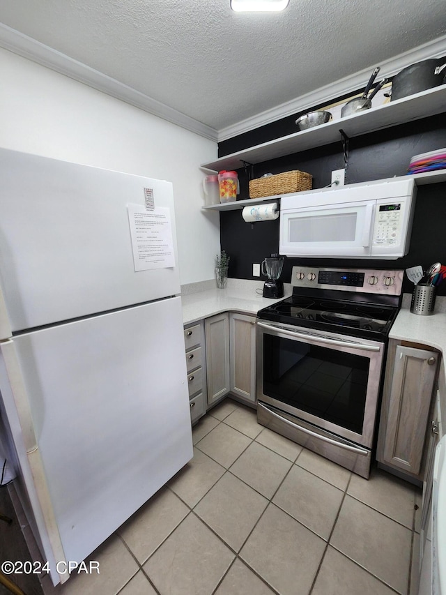 kitchen featuring a textured ceiling, crown molding, light tile patterned flooring, and white appliances