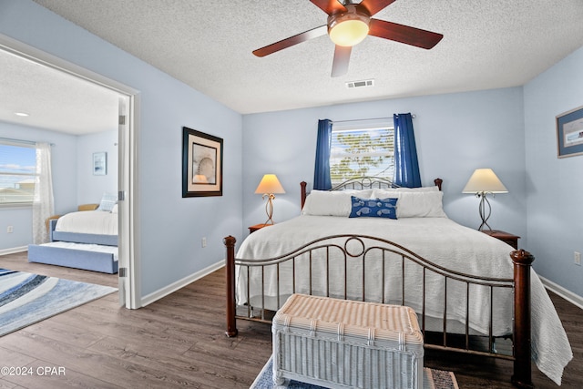 bedroom with ceiling fan, hardwood / wood-style flooring, a textured ceiling, and multiple windows