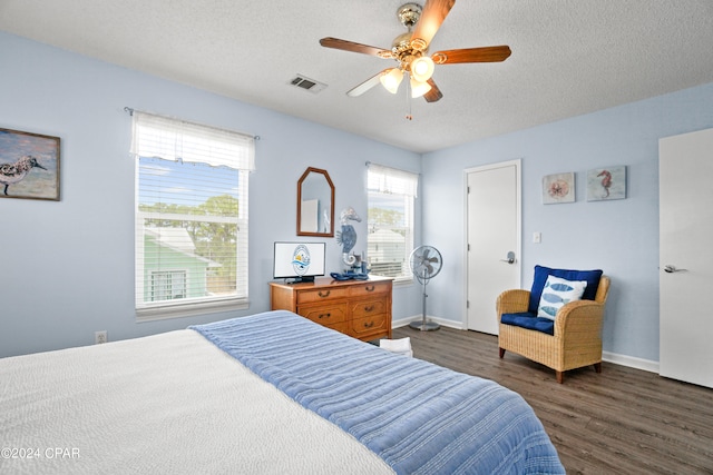 bedroom with ceiling fan, dark hardwood / wood-style floors, and a textured ceiling