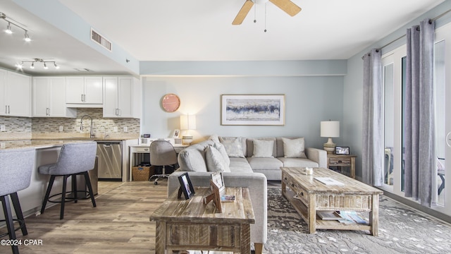 living room featuring ceiling fan, light hardwood / wood-style floors, and sink