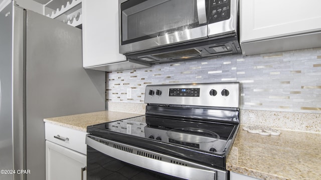 kitchen with white cabinets, backsplash, and stainless steel appliances