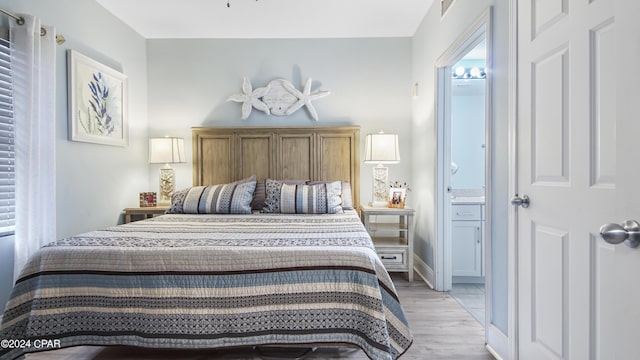 bedroom with ensuite bathroom and light hardwood / wood-style flooring