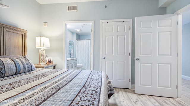 bedroom with ensuite bath, a closet, and light wood-type flooring