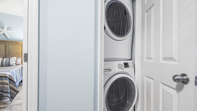 laundry room with light wood-type flooring and stacked washing maching and dryer