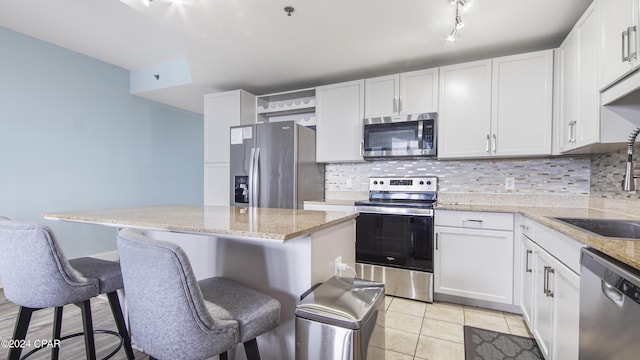 kitchen with white cabinetry, a breakfast bar, a center island, and stainless steel appliances