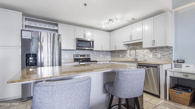 kitchen with sink, a kitchen island, a breakfast bar area, white cabinets, and appliances with stainless steel finishes