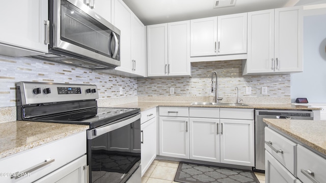 kitchen featuring white cabinets, sink, decorative backsplash, light tile patterned floors, and stainless steel appliances