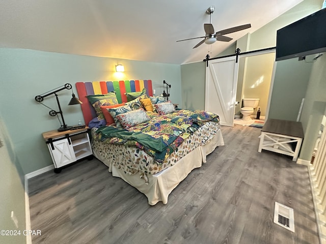 bedroom featuring ensuite bathroom, vaulted ceiling, ceiling fan, a barn door, and hardwood / wood-style floors