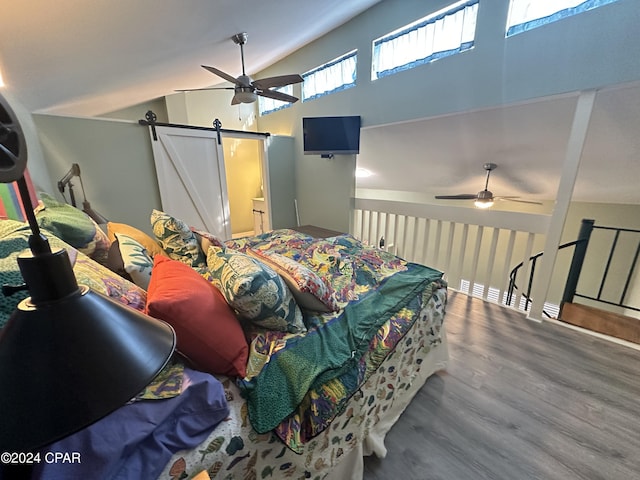 bedroom with hardwood / wood-style floors, a barn door, ceiling fan, and lofted ceiling