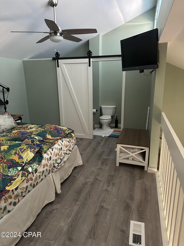 bedroom featuring ensuite bathroom, ceiling fan, a barn door, dark hardwood / wood-style floors, and lofted ceiling