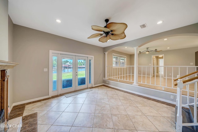 interior space with french doors, decorative columns, light tile patterned floors, and ceiling fan