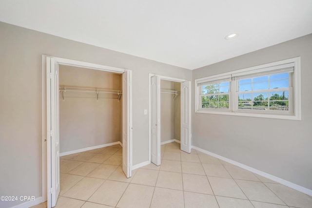 unfurnished bedroom with two closets and light tile patterned flooring