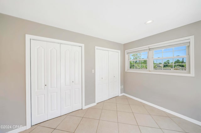 unfurnished bedroom featuring light tile patterned floors and two closets