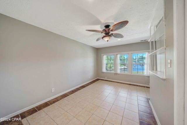 tiled empty room featuring ceiling fan and a textured ceiling