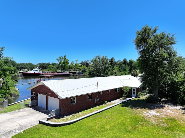 view of front facade with a garage, a water view, and a front lawn