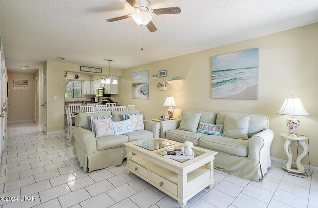 living room with light tile patterned flooring, a textured ceiling, and ceiling fan