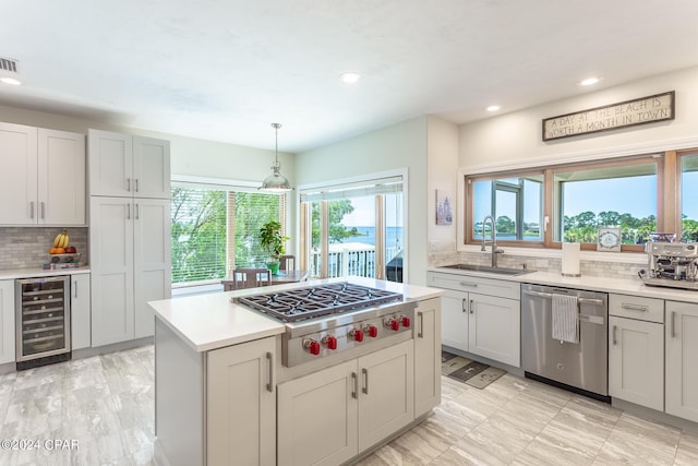 kitchen with hanging light fixtures, wine cooler, sink, appliances with stainless steel finishes, and tasteful backsplash