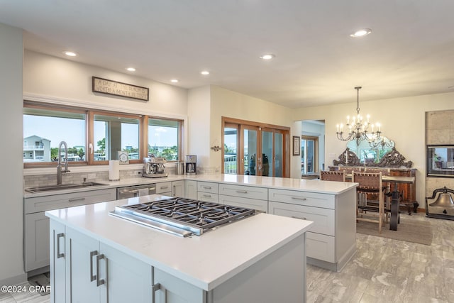 kitchen with kitchen peninsula, stainless steel appliances, sink, decorative light fixtures, and a notable chandelier