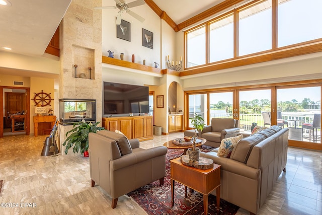 living room with ceiling fan, a towering ceiling, and a tile fireplace