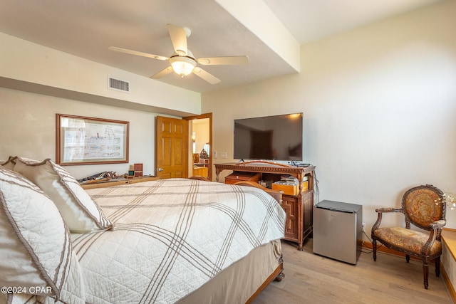 bedroom with ceiling fan, light hardwood / wood-style floors, and fridge