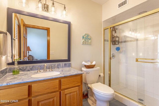 bathroom with vanity, toilet, and a shower with door