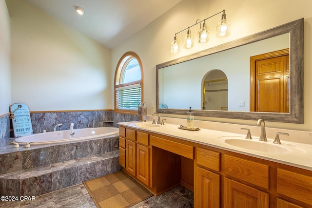 bathroom with vanity, a relaxing tiled tub, and vaulted ceiling