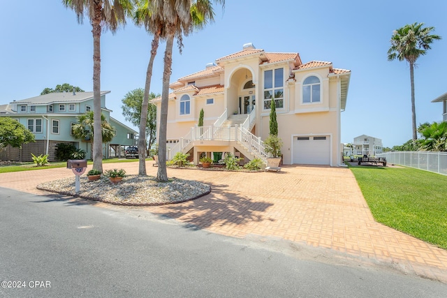 mediterranean / spanish-style house featuring covered porch, a garage, and a front yard