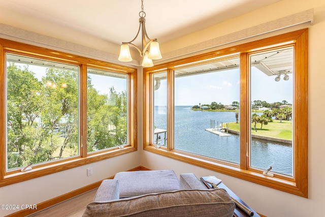 sunroom featuring a water view, a healthy amount of sunlight, and an inviting chandelier