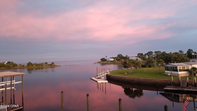 view of dock with a yard and a water view