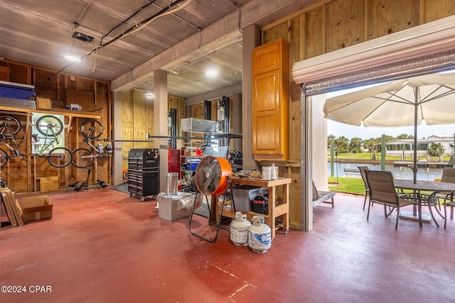 misc room featuring a water view, wooden walls, and concrete floors