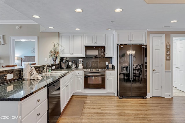 kitchen with black appliances, light wood-style flooring, ornamental molding, a sink, and a peninsula